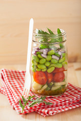 healthy vegetable salad in mason jar: tomato, cucumber, soybean,