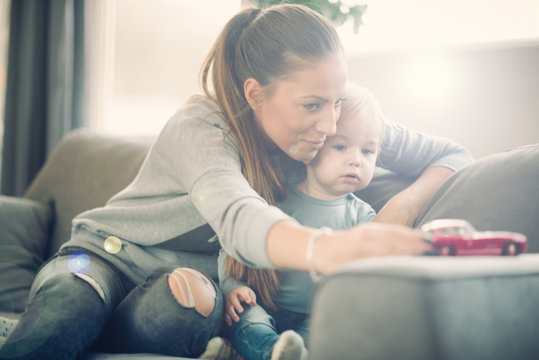 Mom And Her Toddler Son Plays With Red Car In Their Cosy Living Room