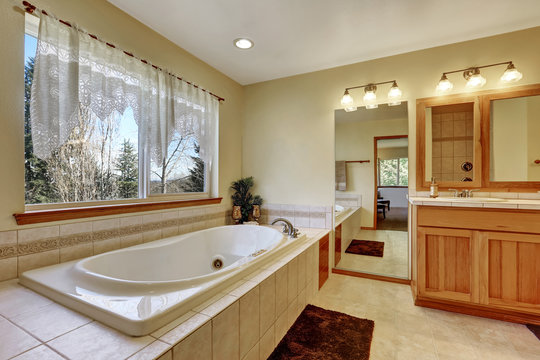 Bathroom interior. White bathtub with beige tile trim