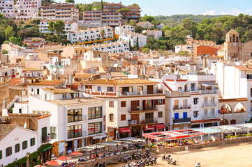 Aerial view of European town on a natural hills with many bars, hotels and restaurants in sunny day with blue sky. Tossa De Mar, Costa Brava, Spain.