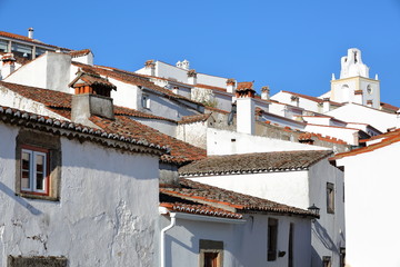 Fototapeta na wymiar MARVAO, PORTUGAL: A typical cobbled street with whitewashed houses and tiled roofs with the Clock Tower in the background