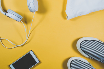 Gadgets and summer clothes on yellow background