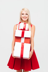 Happy young woman in red dress holding stack of presents