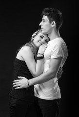 Portrait of happy young couple posing on a dark background. Hugging man and woman. Woman with closed eyes