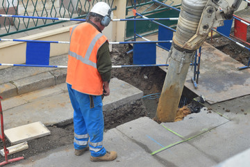 Asphalt worker controls the drilling process. Breaking concrete at road construction site