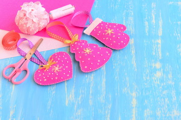 Christmas tree toys. Handicraft pink felt Christmas tree, heart, mitten toys, sewing supplies and materials on blue wooden background with copy space for text. Easy Christmas crafts ideas