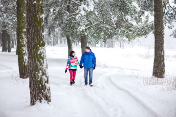 Fototapeta na wymiar Winter walking, young couple in sport wear in snowy winter forest