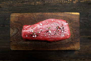 Raw veal meat on a cutting board on a wooden background.Top view.