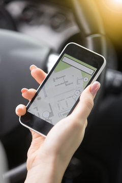 Close up of traveler female hand holding her smart phone. Young woman traveling by car using GPS instead of a paper map, to see destination, checking travel time and distance for available route