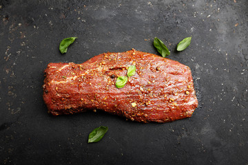 marinated fillet of veal meat on a cutting board on a dark background.Top view.