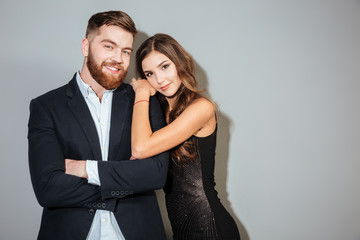 Smiling couple in formal wear embracing and looking at camera