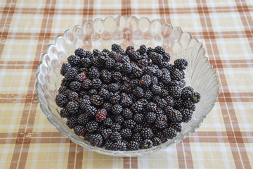 Plate with berries black blackberries. Fruits berries on the table.