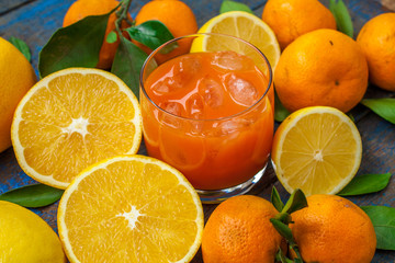 Healthy fresh citrus juice (two glasses), oranges, tangerines, lemons, ice, leaves.  Love for a healthy raw food concept