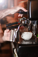 Fototapeta na wymiar Barista prepares cappuccino in his coffeeshop; close-up