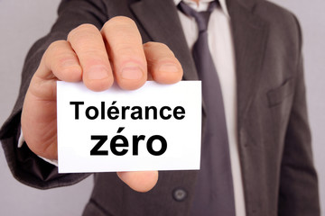 Homme tenant une carte avec tolérance zéro écrit dessus