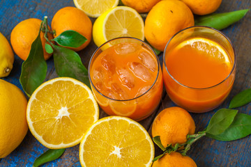 Healthy fresh citrus juice (two glasses), oranges, tangerines, lemons, ice, leaves.  Love for a healthy raw food concept
