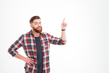 Smiling man in plaid shirt pointing finger up at copyspace