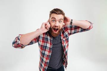 Casual surprised man in plaid shirt talking on mobile phone