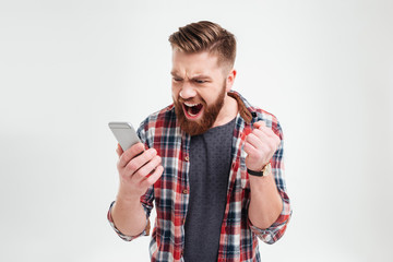 Portrait of angry young man screaming on his mobile phone