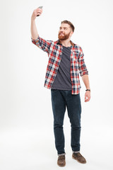 Cheerful bearded man in plaid shirt taking selfie