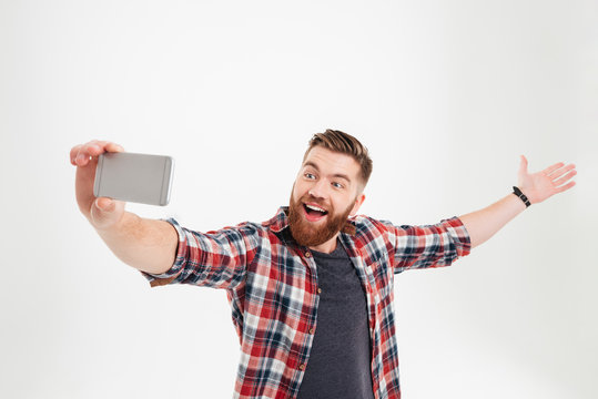 Portrait of a cheerful man taking selfie with raised hand