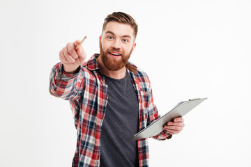 Excited bearded man in checkered shirt pointing pencil at camera