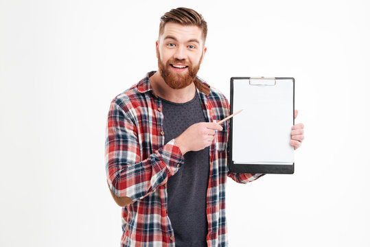 Smiling man in checkered shirt pointing pencil at blank clipboard