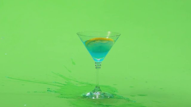 A fresh lemon on a cocktail stick is dropped in slow motion into a glass. Green screen. Slow Motion.