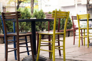 Fototapeta na wymiar Colourful tables and chairs in a cafe garden.