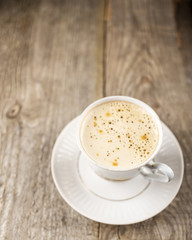 Delicious cup of coffee with foam on the old wooden table