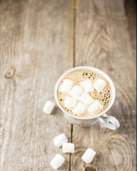 Hot black coffee in a cup with marshmallows on the old a wooden table