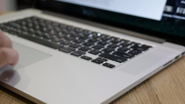 Male hands open laptop and start working, Hand fingers using touchpad of laptop computer for scrolling pages searching in internet. slider shot, pan left