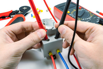 Measurement of voltage in electrical outlet with a multimeter on a white background