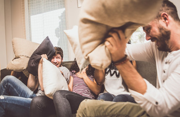 Friends having fun on the couch and making pillow fight