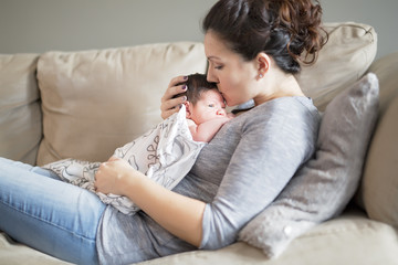 Happy mother holding adorable child baby on the living room