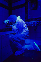 Criminologist working under UV light on place of crime