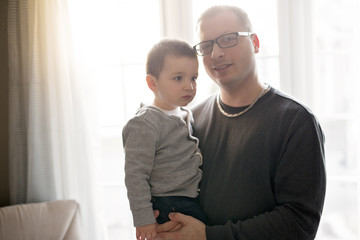 Young father and his child in front of the window