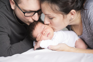 Happy family with newborn baby on the bed in the room
