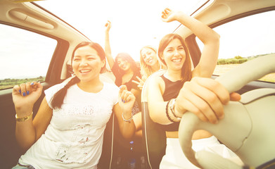 Women having fun driving in a convertible car