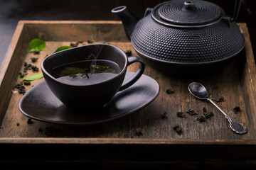 Teapot and cup with green tea on a wooden