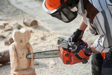The sculptor carves the wood with the chainsaw