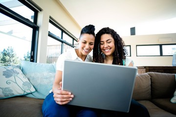Lesbian couple smiling while using laptop