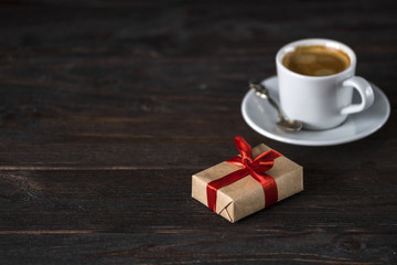 cup of aroma black espresso on wooden table with little present
