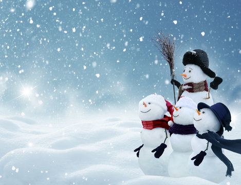  snowmen standing in winter Christmas landscape.