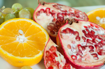 спелые, сочные фрукты: яркий красный гранат, сочный апельсин, виноград