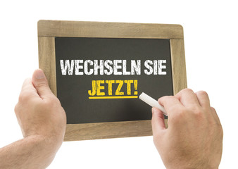 Wechseln Sie Jetzt! Hand schreibt auf Kreidetafel
