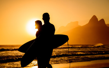 Golden sunset in Ipanema Beach with Two Brothers, Dois Irmaos, Mountain and two surfers...