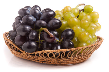 bunch of green and blue grapes in  wicker basket isolated on white background