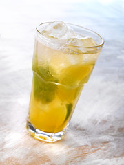 Gold drink with ice. Photographed on a light wooden background. Light illumination.