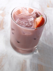 Gold drink with ice. Photographed on a light wooden background. Light illumination.